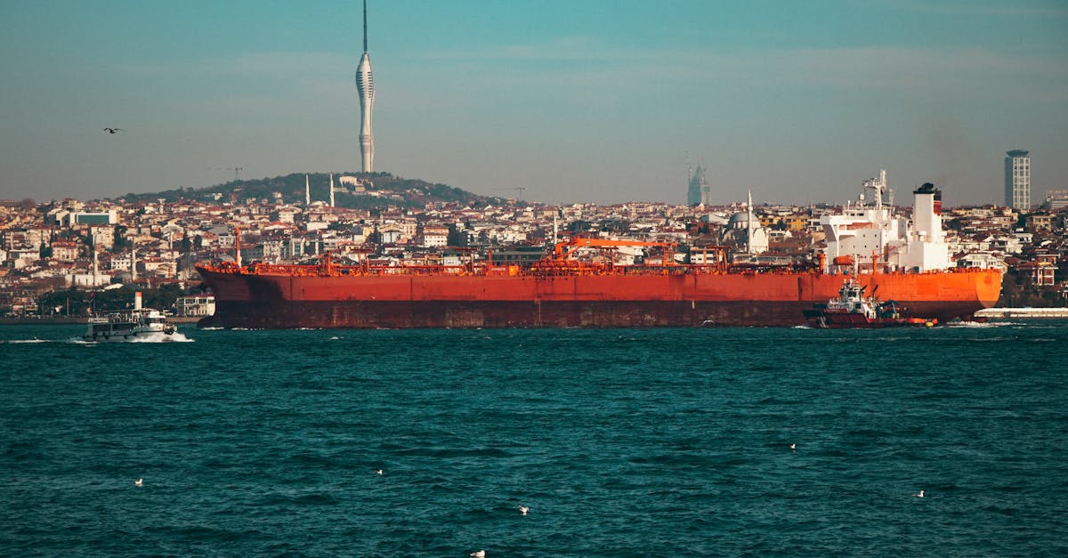 Oil tanker passing through a strait, with city skyline in the background