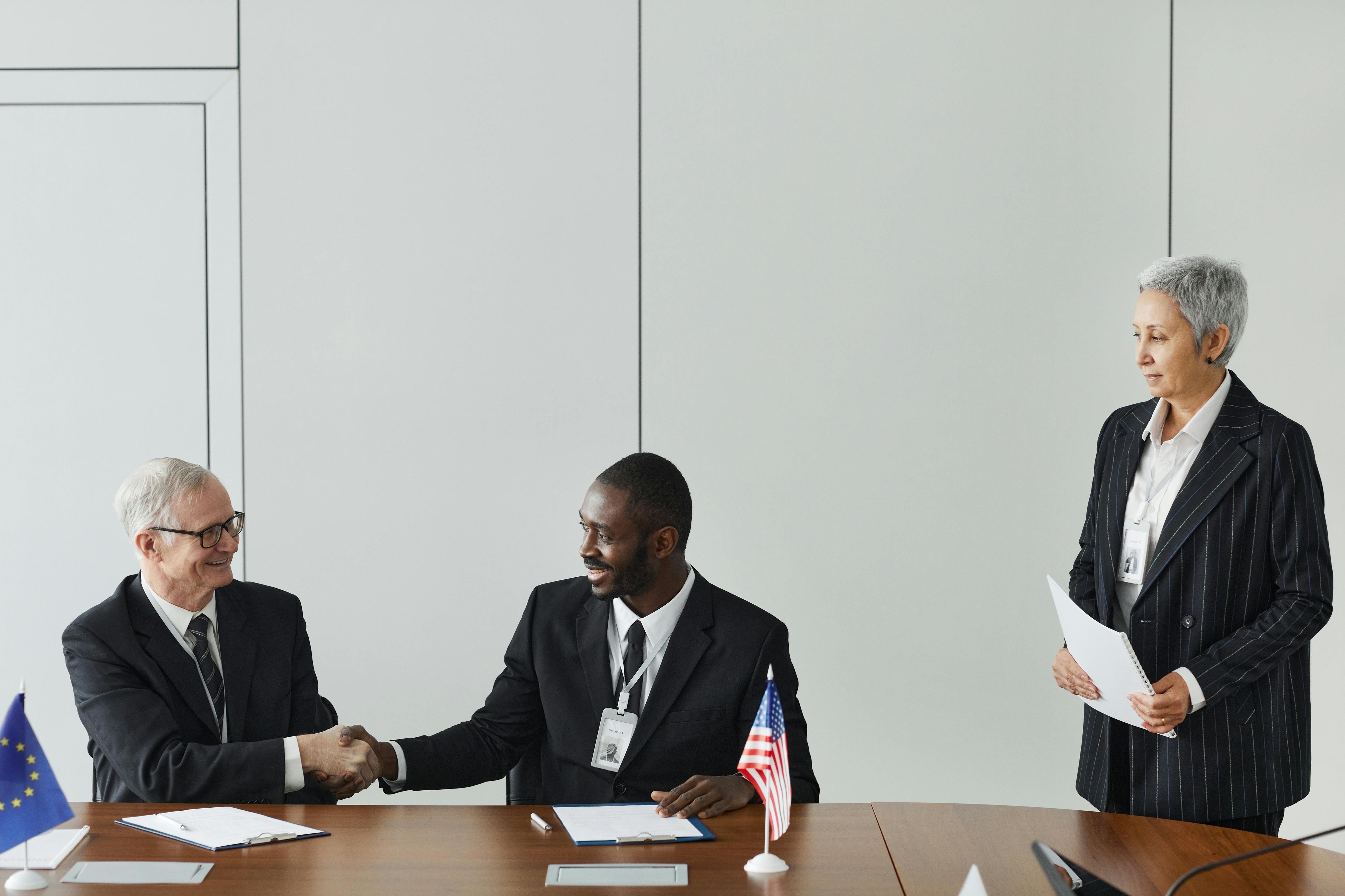 Officials signing a multilateral agreement at a conference table with national flags
