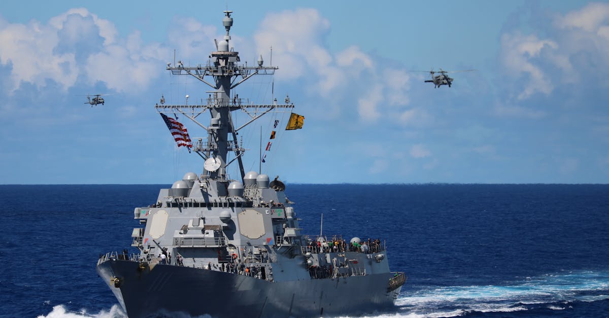 A US Navy destroyer at sea with helicopters in formation overhead.