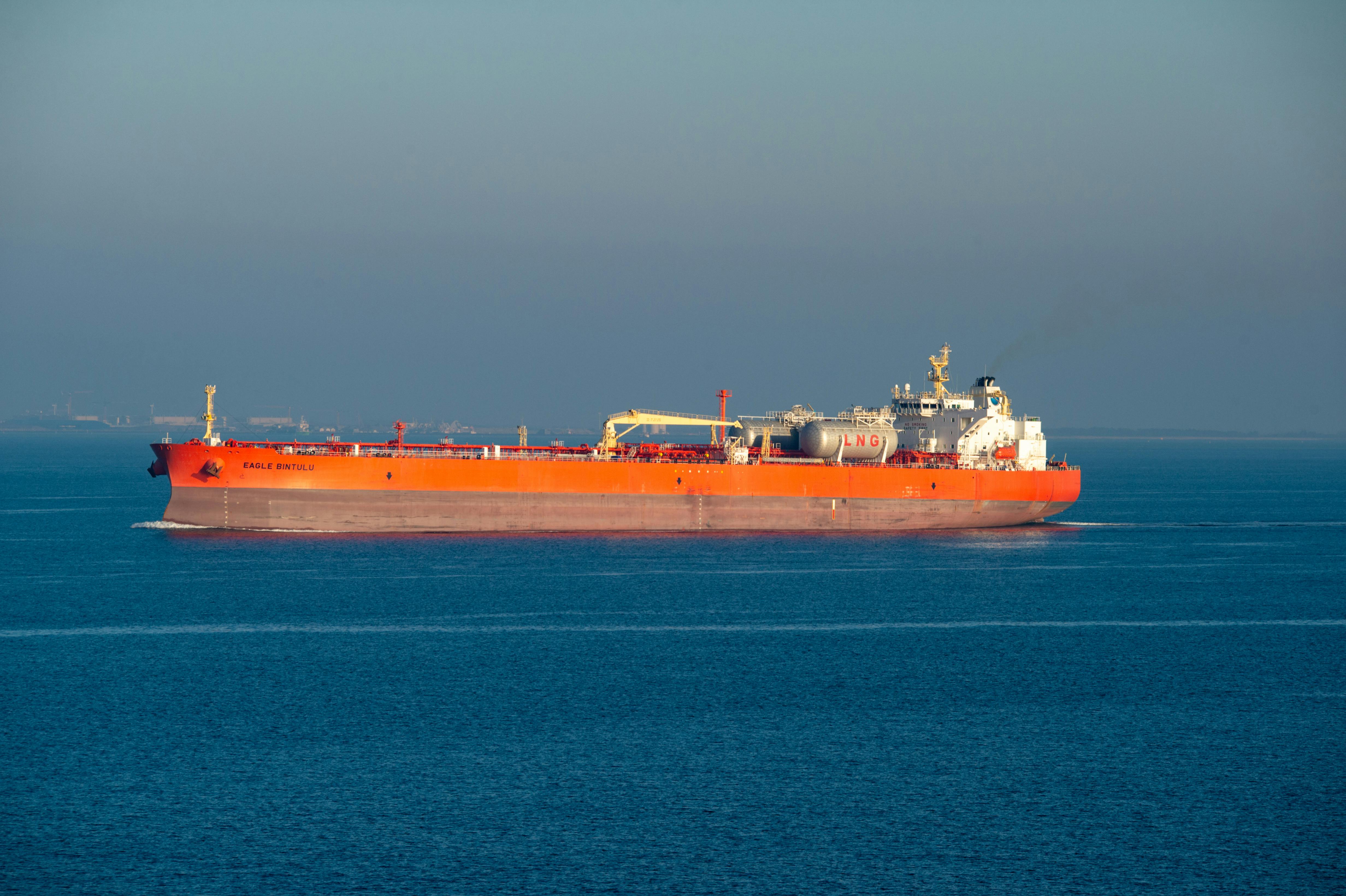 Orange LNG carrier ship cruising through calm sea waters on a clear day